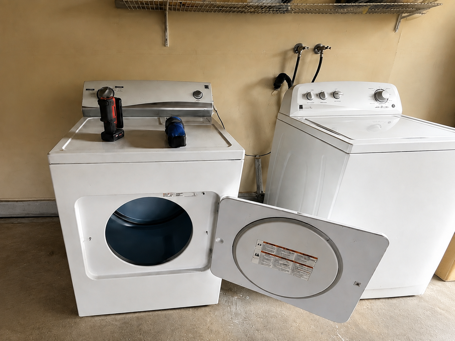 Front-load dryer undergoing professional appliance service beside another laundry unit